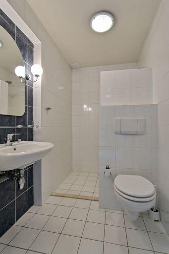 Badkamer 1 is geheel betegeld en voorzien van een toilet, een