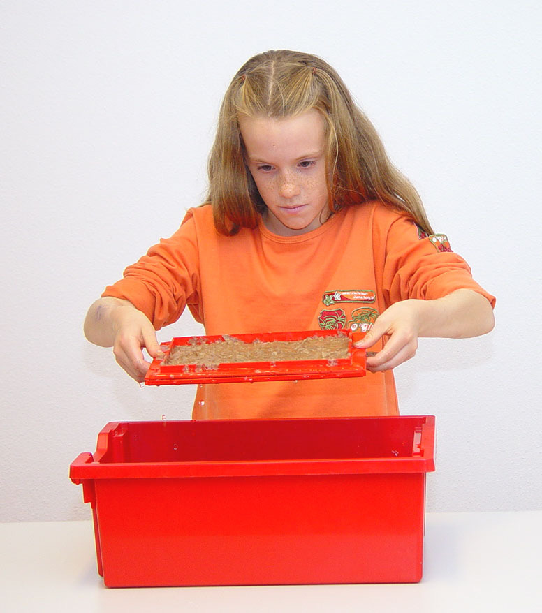 A3 1. Leg op tafel een krant en daarop één blad viltpapier klaar. Leg nog een krant en een blad viltpapier klaar. 2. Zet de zeef en de scheprand op elkaar. Zorg dat de pinnetjes in de gaatjes vallen.