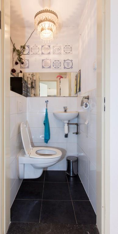Badkamer en toilet: De badkamer is eveneens bereikbaar vanuit de hal en is uitgevoerd met lichte wandtegels en antracietgrijze vloertegels.