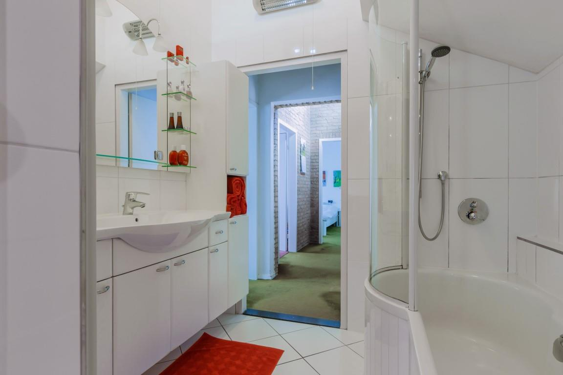 De badkamer: De badkamer is neutraal wit betegeld en voorzien van een ligbad met een speciale douchehoek en een groot