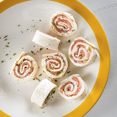 Wrap met gerookte zalm en verse kaas Benodigdheden voor 6 hapjes 1 wrap 3 plakjes gerookte zalm 125 g verse kaas ½ komkommer 1/2 teentje knoflook 1 tl olijfolie peper zout Prikkers Schil de komkommer