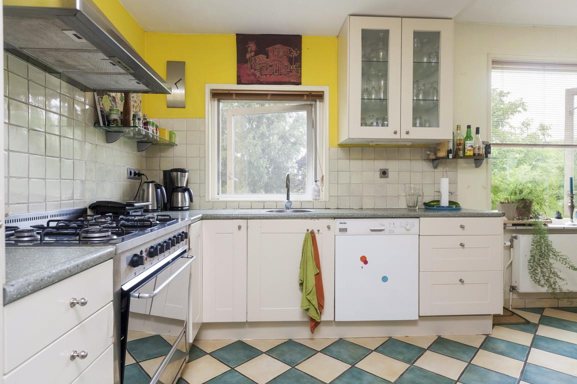 De sfeervolle woonkeuken is voorzien van een gaskomfoor, oven, koelkast en dubbele spoelbak.