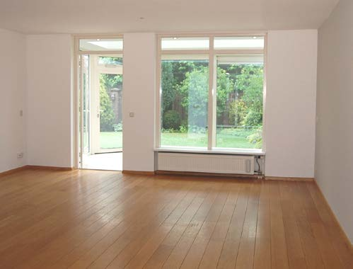 De woonkamer van deze woning is voorzien van een massief eiken houten vloer en moderne gladde stucwerk wand- en plafondafwerking.