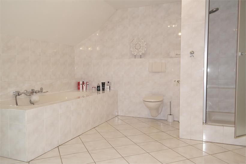 De royale badkamer is volledig licht betegeld, met vloerverwarming, en een stucwerk plafond.