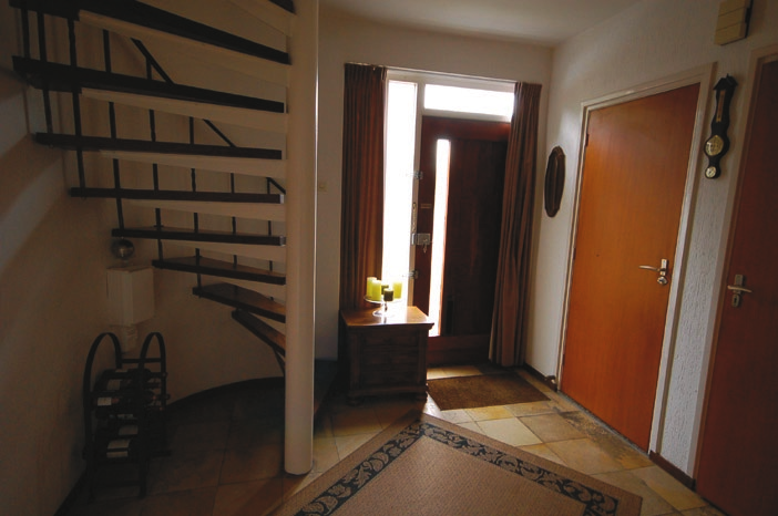 trapopgang naar de eerste verdieping vindt. De hal heeft toegangsdeuren naar de woonkamer en keuken.