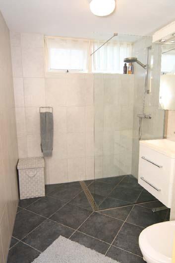 thermosstaatkraan, toilet, wastafel met wandmeubel en inbouwspots.