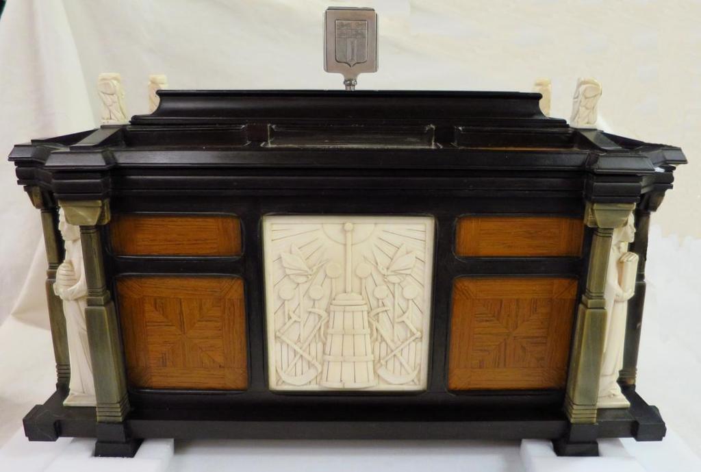 Het rechthoekige kistje bestaat verder uit een ebbenhouten frame ingelegd met palissanderhout met geometrische motieven, met op de hoeken nissen met zinnebeeldige figuren van ivoor geflankeerd door