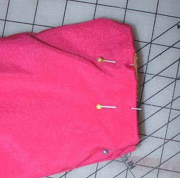 Knip de naadtoeslagen in de ronddingen korter. Knip de hoeken schuin af. Keer de jas en schuif hem goed in elkaar.