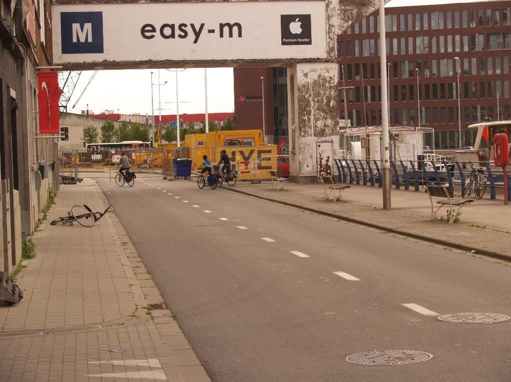 Veel fietsers die van het plein voor OPEK komen rijden niet op de weg, maar op de strook naast het water, tussen de banken.