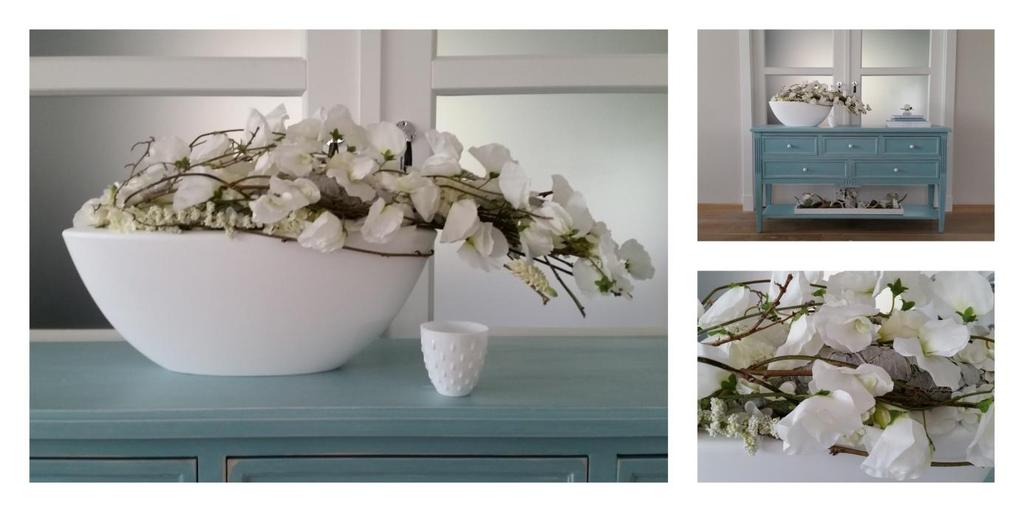 Modern wit bloemstuk in witte ovale vaas Een modern bloemstuk met takken en witte zijden bloemen in een