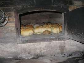 bakkers met de keerwis (een stok met een dweil eraan) de oven uitdweilen. Op deze manier wordt de oven schoon gemaakt.