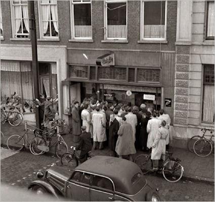 vraag 58 Foto uit 1950 Op de foto zie je mensen die zich verdringen voor de etalage van een winkel. Er staat een apparaat dat sinds kort te koop is.