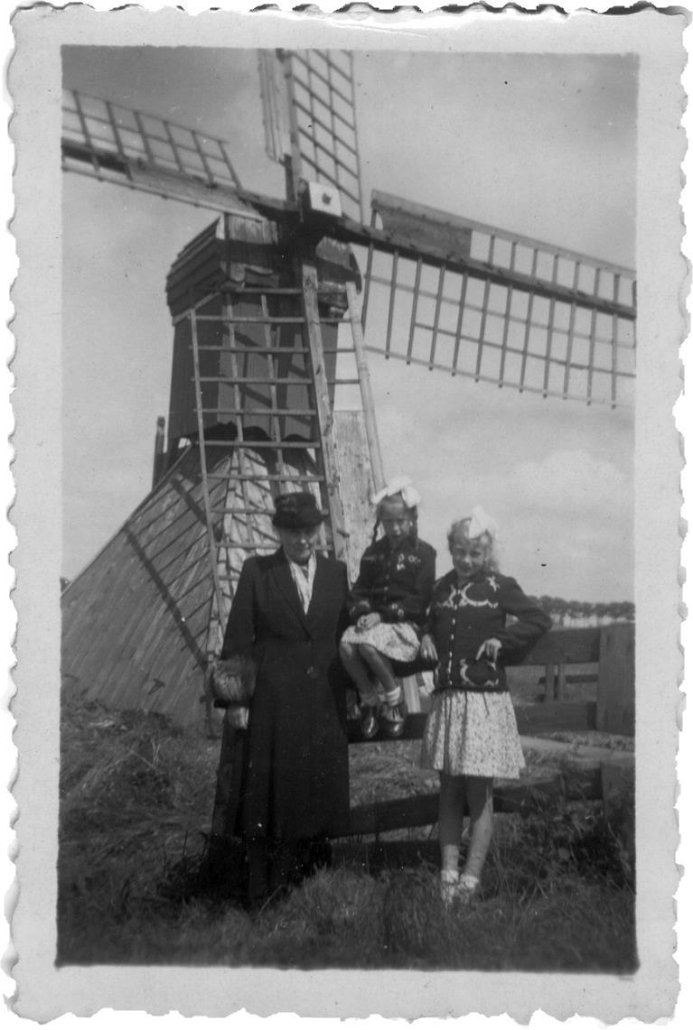 Bij de foto uit het album van mevr. Hoogland: Als er een foto gemaakt werd diende de molen vaak als decor. Hier met beppe Hiltje Bruinsma en de beppesizzers Hessie en Hillie (rechts). Gerben D.