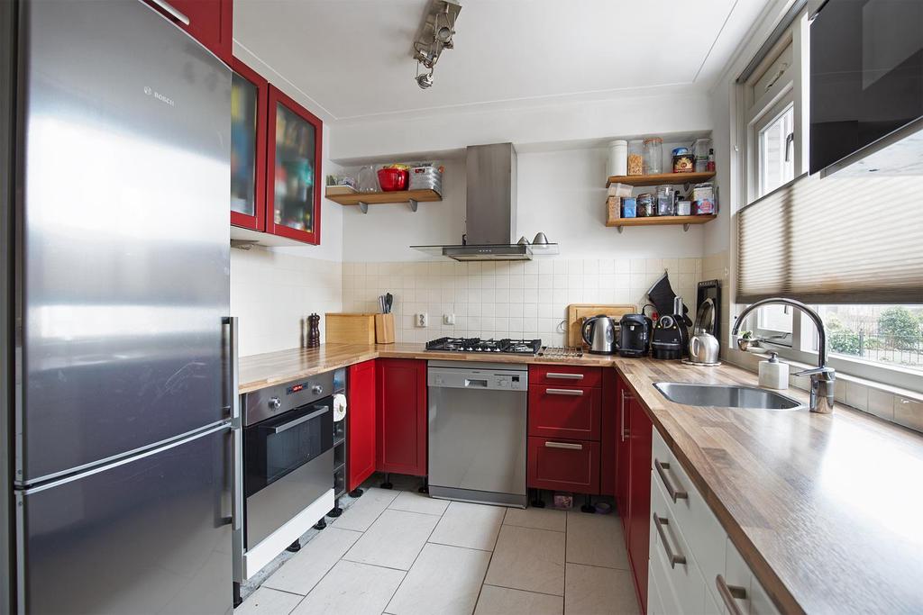 Halfopen keuken aan de voorzijde Aan de voorzijde gelegen halfopen keuken uitgevoerd met crème en bordeaux rode keukenkastjes en een kunststof aanrechtblad (houtmotief) voorzien van een enkele RVS