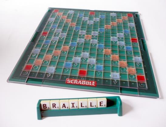 Blokjes met zwarte letters op witte achtergrond, voorzien van brailleindicaties.