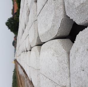 Dit wordt bedekt met een laag steen (split) en afgesloten met een betonnen band. Op de laag steen, tegen de betonnen band aan, worden betonzuilen gelegd.