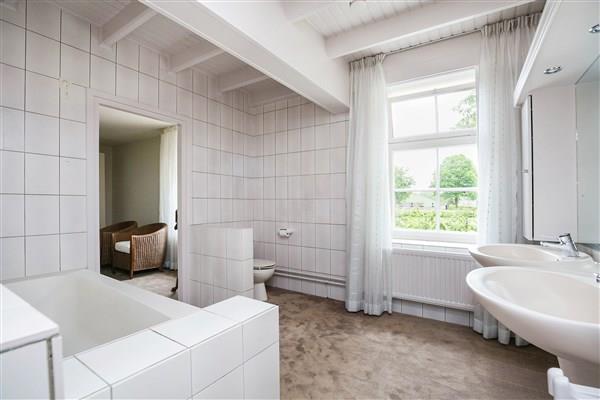 De badkamer is eveneens afgewerkt met vloerbedekking en voorzien van betegelde wanden en een licht geschilderd