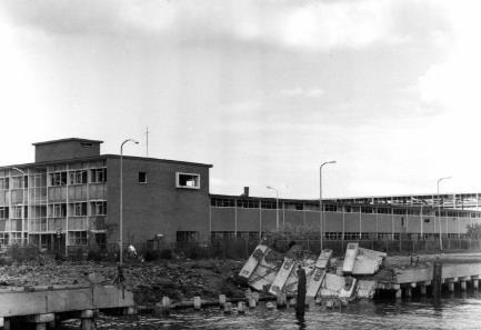 Het bijschrift luidt: Gezicht op de vernielde loswal langs de Kernkade te Utrecht, na de ontploffing van een munitieschip in de Kernhaven. Op de achtergrond het beschadigde gebouw van de N.V.