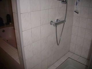 Bad- doucheruimte Douche/toiletruimte aanbouw Toiletruimte Los/hol klinkend tegelwerk onder douchekraan, zichtbaar bollend.