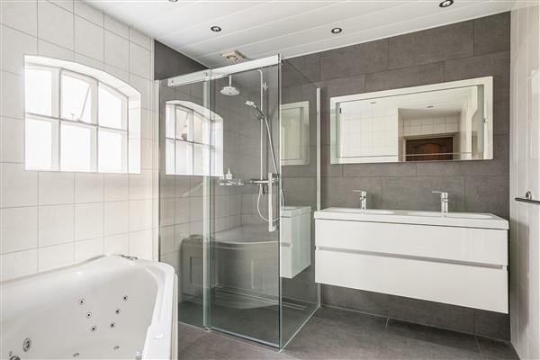 De ruime, geheel betegelde badkamer is onlangs geheel vernieuwd