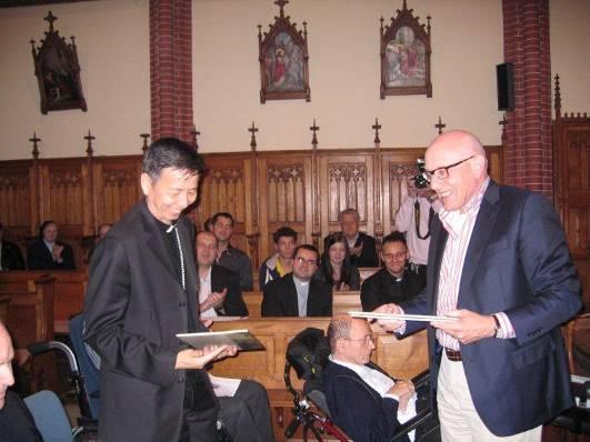 Voorzitter van de Mgr. Schraven Stichting, Harry Schraven, overhandigt het stripboek aan de Chinese aartsbisschop Savio Hon Tai Fai in de kapel van de Lazaristen te Panningen.