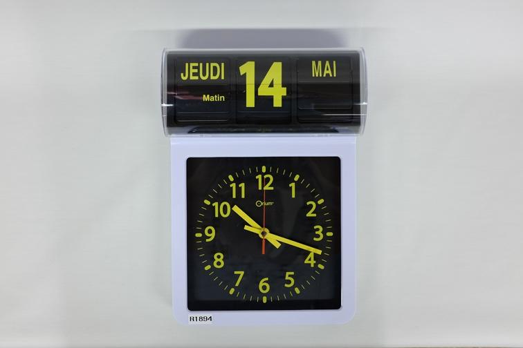 Analogische klok, grote gele aanduiding op zwarte achtergrond voor een maximaal contrast. De datum wordt vermeld in het frans.