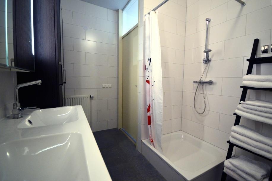 Moderne badkamer met ligbad, separate douche en dubbele vaste wastafel in een ombouwmeubel. Separaat toilet met een fonteintje.