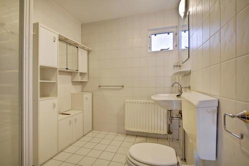 Badkamer met wastafel, douche, wc en betegeling tot plafond.