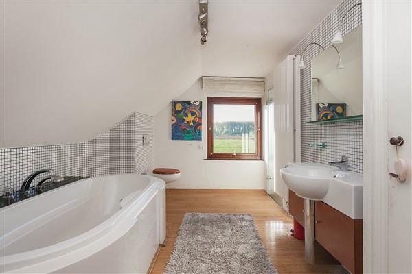 De geheel betegelde badkamer is uitgerust met een ligbad met douchescherm, een vaste wastafel, een zwevend toilet.