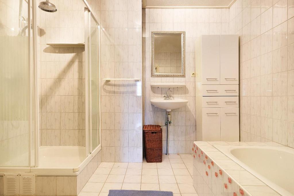 Tevens bevindt zich op de begane grond de badkamer met ligbad, douche en vaste