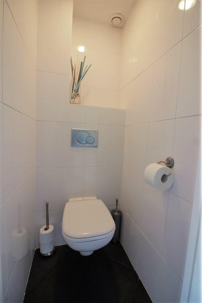 Net als de woonkamer en keuken is de vloer voorzien van laminaat en zijn wanden strak gestuukt. De toiletruimte is modern uitgevoerd met half hoog tegelwerk en een zwevend toilet.