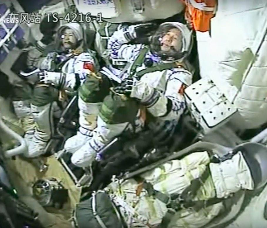 Chen Dong (l) en Jing Haipeng (r) salueren vanuit hun capsule vlak voor hun vertrek Het toestel arriveerde op dinsdagavond 18 September te 21.31 uur Nederlandse tijd bij het ruimtestation.