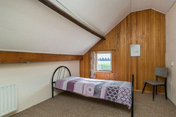 Slaapkamer III is voorzien van vloerbedekking, de wanden zijn deels behangen en deels betimmerd en een stucwerk plafond.
