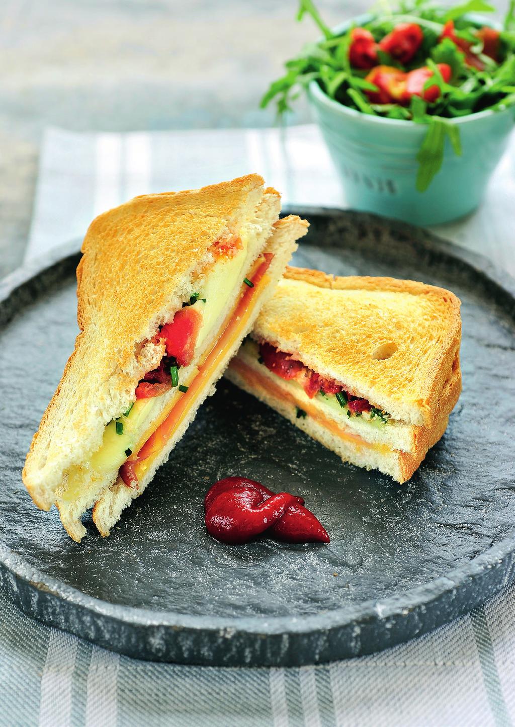 Tosti s 3 sneetjes brood 1 plak gekookte ham 1 plak jong belegen kaas 4 plakjes mozzarella 5 gedroogde tomaatjes beetje bieslook Beleg een snee brood met jong belegen kaas en leg daar een plak ham op.