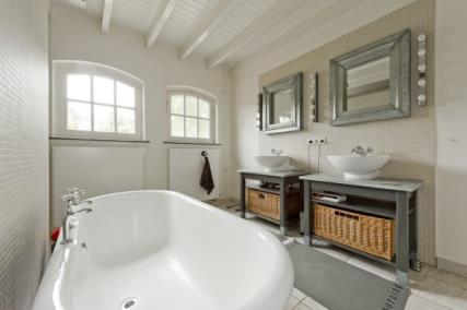 Ook de badkamer heeft een houten balken plafond in een lichte kleurstelling.
