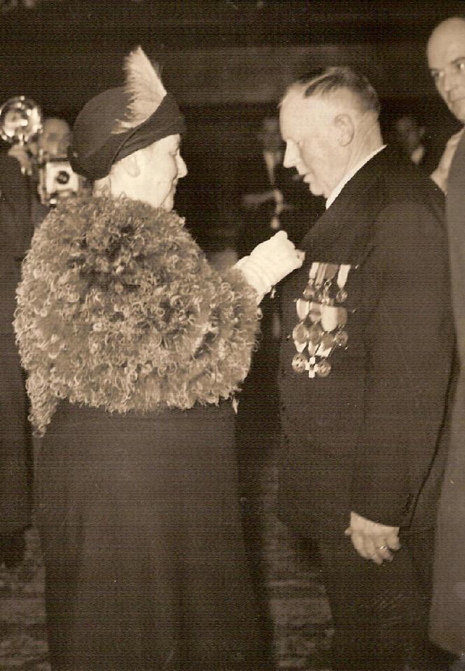 Prinses Wilhelmina reikt tijdens de viering van het 125 jarig bestaan van de Reddingsmaatschappij in 1949 een medaille uit aan Mees Toxopeus schipper van de Insulinde Het bestuur kijkt vol tros naar