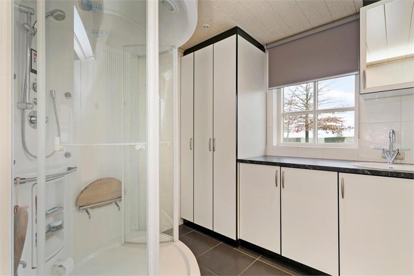 Volledig licht betegelde badkamer met elektrische vloerverwarming en een MDF plafond met inbouwspots.