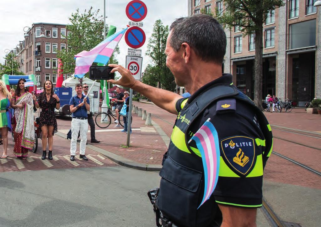 Een politieagent begeleidt een vrolijke optocht in het kader van de Gay Pride. Demonstranten kunnen alle onderdelen van de samenleving vertegenwoordigen.