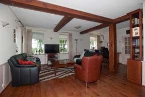 L-vormige woonkamer voorzien van een houten vloer met kelder, moderne keuken voorzien van diverse inbouwapparatuur en