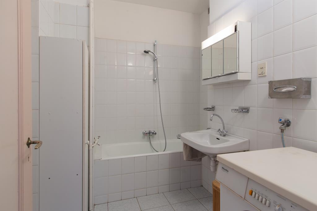 Badkamer Nette inpandige badkamer met ligbad en wastafel. De wanden en vloer zijn wit betegeld.