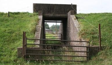 NV Erlecom (zie tekening). Deze poort is aangelegd om in de uiterwaard grond te tichelen. Het smalspoor via het bruggat dwars door de Erlecomsedam is duidelijk zichtbaar.