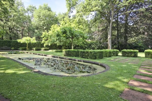 volwassen bomen, een uitgestrekt gazon en een grote vijver.