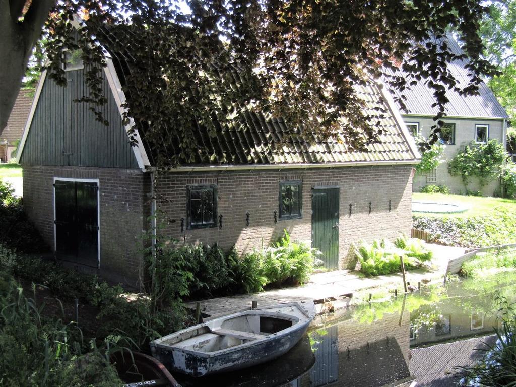 De schuur weerspiegelt in de sloot. De foto is gemaakt vanaf de brug.