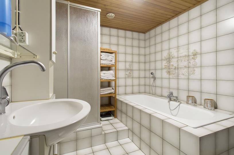 De badkamer op de begane grond is afgewerkt met tegels als vloeren wandafwerking en schrootjes als plafondafwerking.