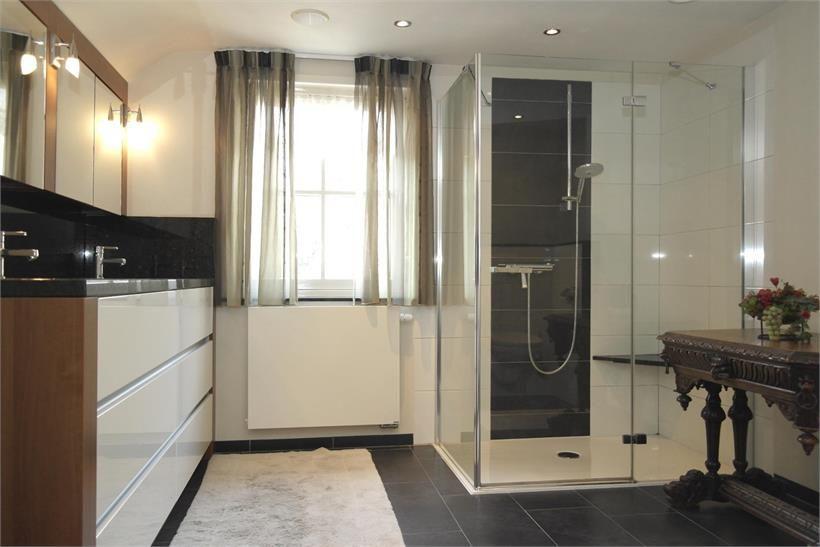 Een ruime, moderne badkamer met een tegelvloer, volledig