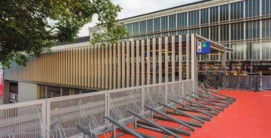 DE RITMISCHE LAMELLENGEVEL ZOEKT AANSLUITING BIJ DE MONUMENTALE STOOMKAPPEN VAN HET STATION IN HET DONKER FUNGEERT DE FIETSGEVEL ALS STEDELIJKE LAMPION FIETSGEVEL De gestapelde