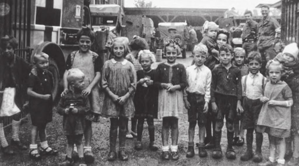 September 1944, deze foto is gemaakt door de Amerikaanse korporaal Small. Kinderen komen op het schoolplein kijken naar hun bevrijders en hopen op chocolate en chewing-gum.