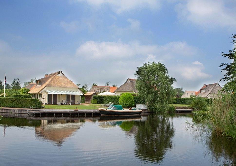 Woonkamer met plavuizen vloer, open keuken, openslaande tuindeuren naar terras en elektrisch zonnescherm.