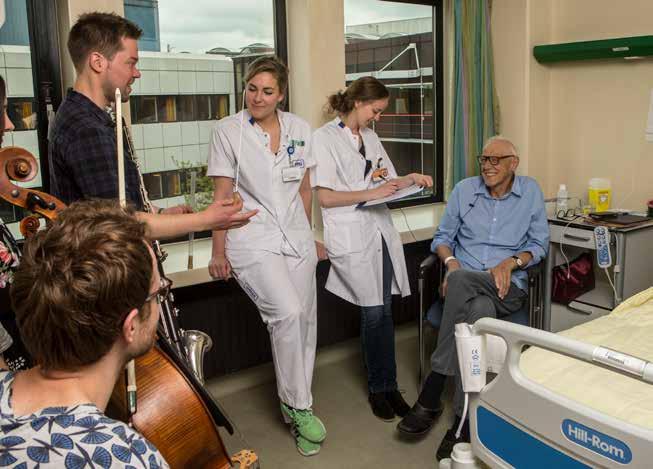 Klarinettist Jesse biedt een patiënt de dirigeerstok aan voor het leiden van een improvisatie Lectoraat Lifelong Learning in Music Prof. dr.