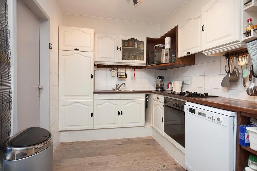 Aansluitend aan de woonkamer bevindt zich de nette keuken in L-opstelling, voorzien van inbouwapparatuur: 4-pits